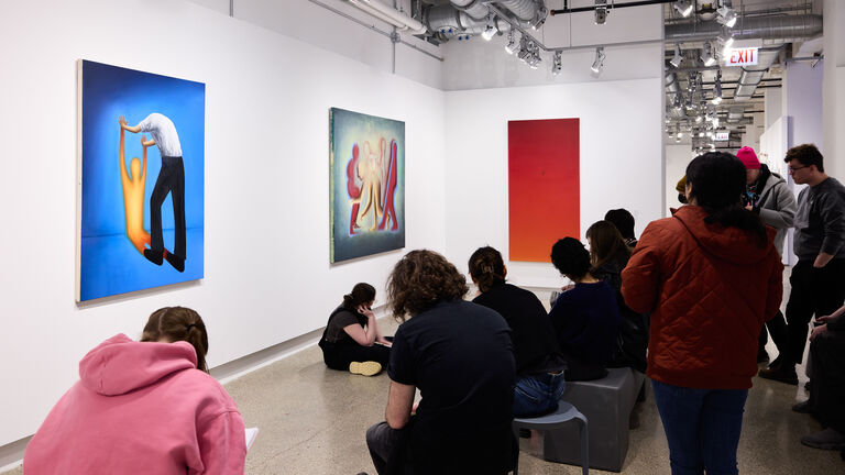 A group of students looking at colorful artwork in a gallery